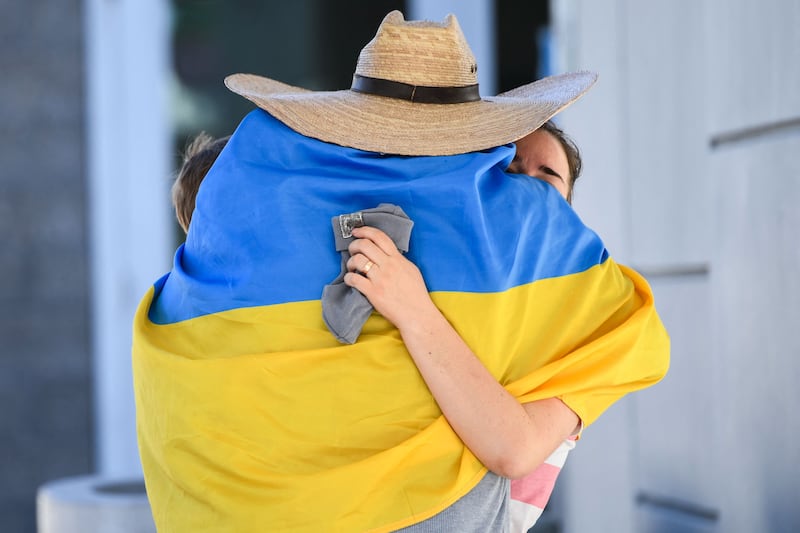 A man wrapped in a Ukrainian flag embraces a refugee in southern California. AFP