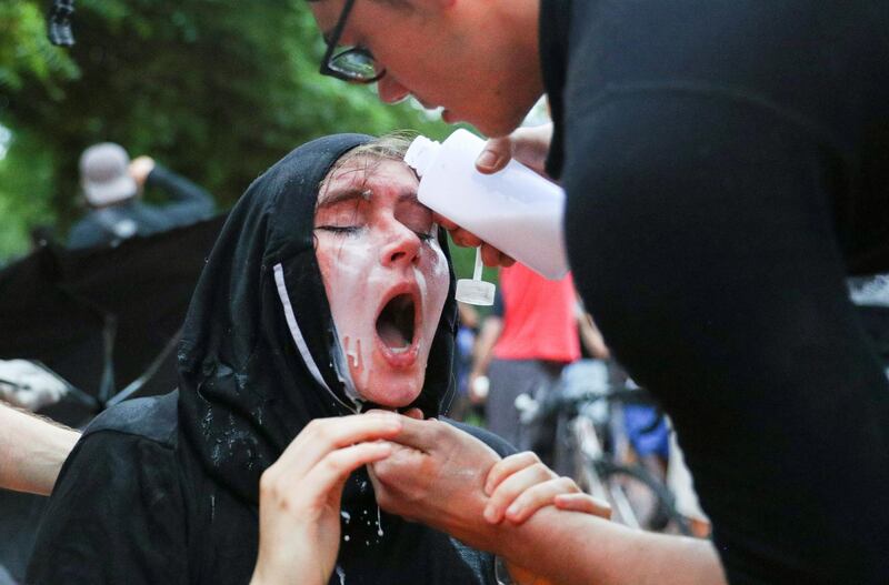 A man treats a woman affected by pepper spray as Washington Metropolitan Police officers clash with demonstrators trying to pull down the statue of U.S. President Andrew Jackson in the middle of Lafayette Park. Reuters