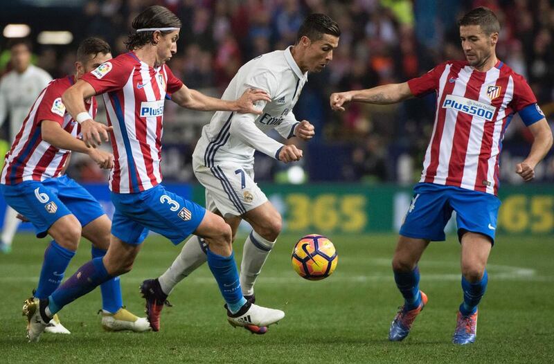 Real Madrid’s Portuguese forward Cristiano Ronaldo, centre, vies with Atletico Madrid’s Brazilian defender Filipe Luis. Curto de la Torre / AFP