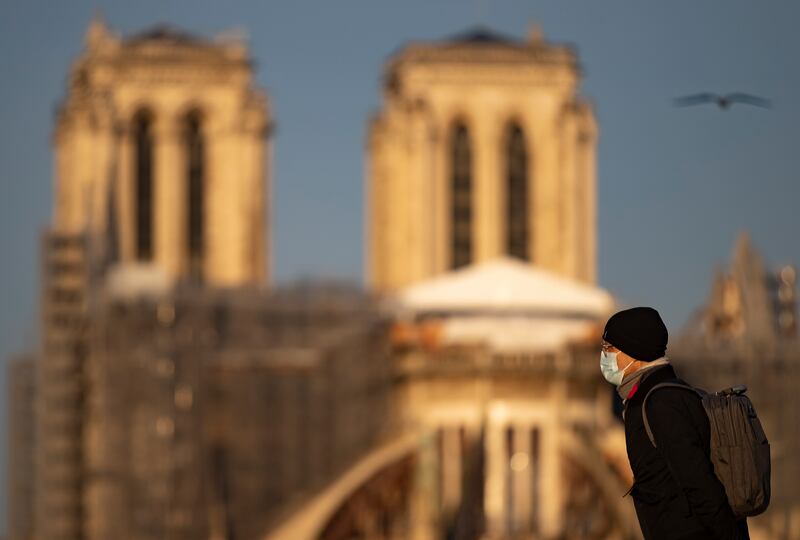 A pedestrian wearing a protective face mask walks near Notre-Dame Cathedral, in Paris.  Nearly 57,000 new Covid-19 infections are being reported in France every 24 hours. EPA