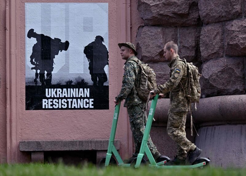 Ukrainian servicemen ride electric scooters in Kyiv. AFP