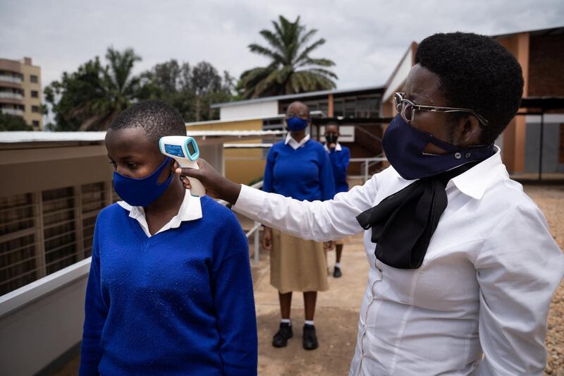 Schoolgirls get their temperature measured before the first class in about eight months at at Lycee Notre dame de Citeaux school in Kigali, Rwanda, on November 2, 2020, following schools' closure country wide due to the COVID-19 coronavirus pandemic outbreak. (Photo by Simon Wohlfahrt / AFP)