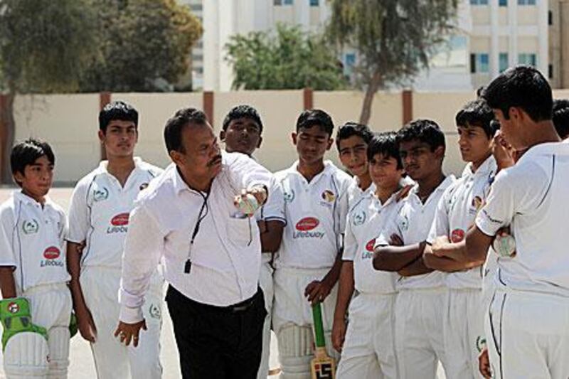 A coach with the Abu Dhabi Indian school Under 16 Cricket team goes over how to deliver a certain spin on things during their practice session at their school ground in Abu Dhabi.