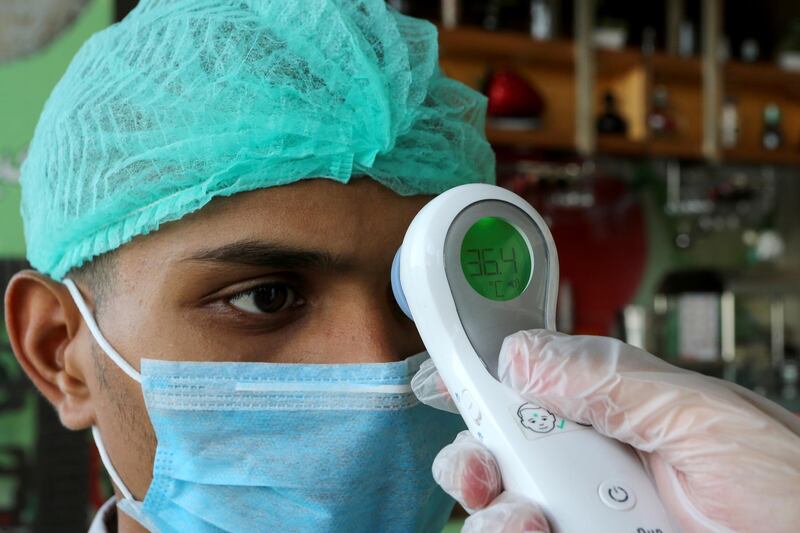 A manager wearing protective gloves checks the temprature of a worker amid the coronavirus pandemic at a restaurant, in Riyadh, Saudi Arabia, on April 26, 2020. Reuters