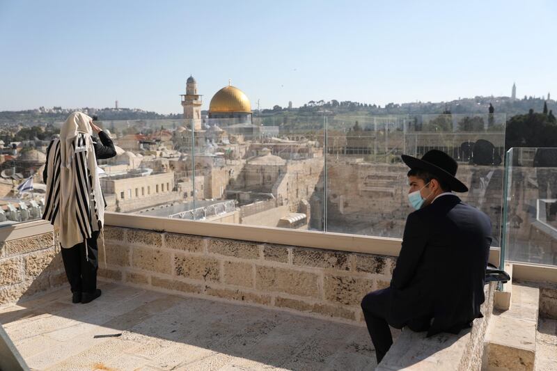 epa08358267 Orthodox Jews pray and keep distance from each other while wearing a protective face mask as they recite the Priestly Blessing on the high holiday of Passover on a rooftop in front of the Western Wall, in Jerusalem, Israel, 12 April 2020. Media reports state, that according to government decision, Israeli police have approved a small prayer while enforcing lockdown on several cities and ultra-Orthodox Jewish neighborhoods across the country in order to prevent the spread of the SARS-CoV-2 coronavirus during the holidays season.  EPA/ABIR SULTAN