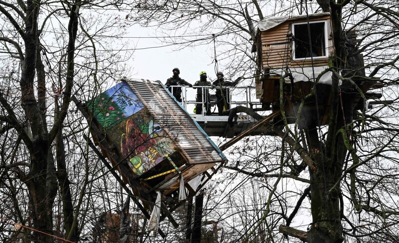 Police tear down a treehouse of environmentalists in the village of Luetzerath, western Germany, on January 12, 2023, as the evacuation continues of anti-coal activists staging an 'active defence' of the village, ahead of a planned demolition to expand a coal mine.  - German police pressed ahead with clearing a camp of anti-coal activists in the abandoned town of Luetzerath which has become emblematic of the country's struggle to transition away from fossil fuels amid an energy crisis.  Once numbering as many as 2,000, around 200 anti-coal activists remain in the village, which has been slated for demolition to enable the expansion of the neighbouring Garzweiler coal mine.  (Photo by INA FASSBENDER  /  AFP)