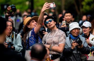 A couple poses for a selfie as they arrive at the Shanghai Fashion Week in Shanghai on March 31, 2018. / AFP PHOTO / Johannes EISELE