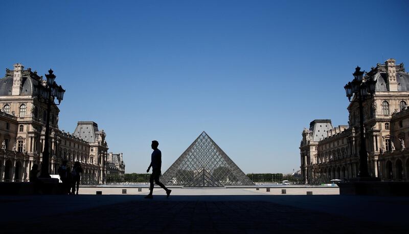 A man walks near the Louvre Pyramid designed by Chinese-born U.S. architect Ieoh Ming Pei during a warm and sunny day in Paris as a heatwave hits France, June 25, 2020. REUTERS/Gonzalo Fuentes