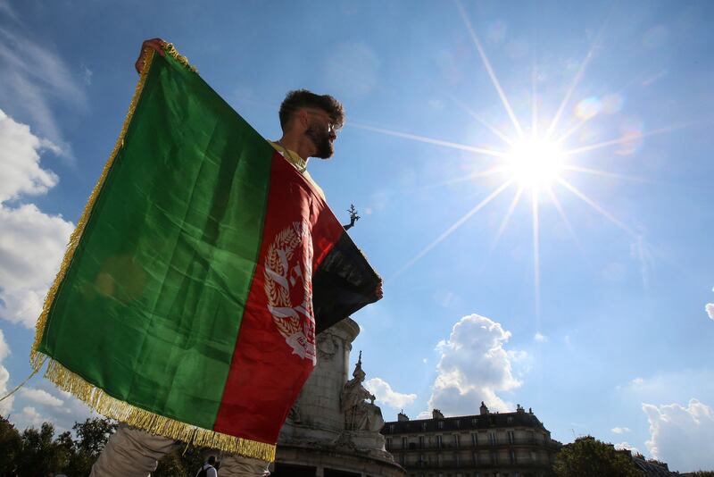 A man holds the Afghan national flag as he takes part in a rally in support of Afghanistan's people, at the Place de la Republique, in Paris. AFP