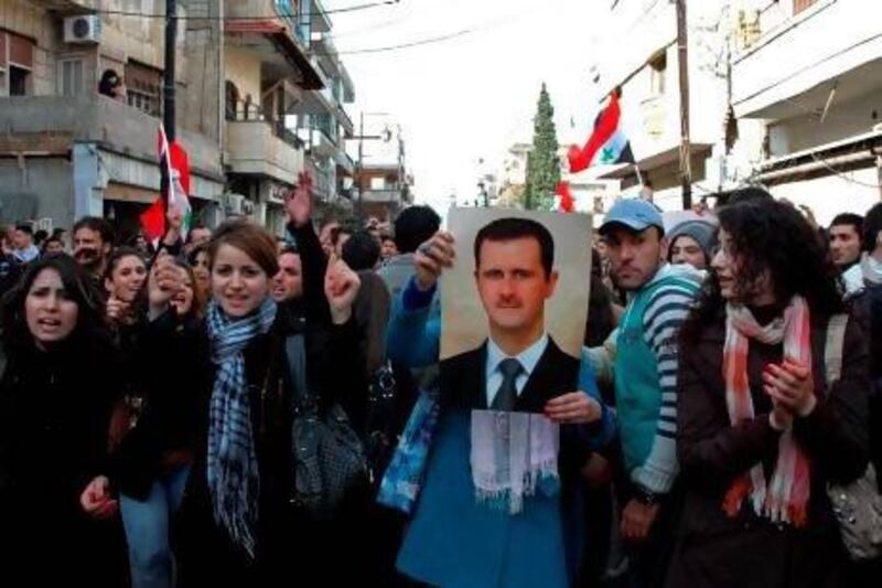 Syrian demonstrators wave a portrait of their embattled president Bashar Al Assad during a march in his support in the central city of Homs on Sunday.