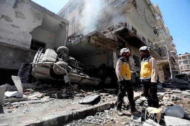 Members of the Syrian Civil Defence, known as the White Helmets, gather at the site of a reported air strike on the town of Ariha, Idlib province on July 28, 2019. AFP