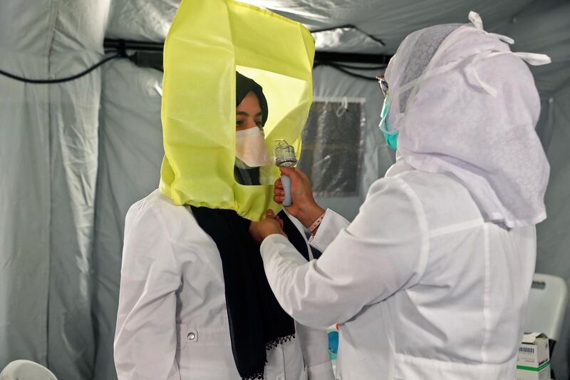 A medical worker assists another to dress up in protective gear at a tent in a newly opened field hospital in Makkah in Saudi Arabia.   AFP