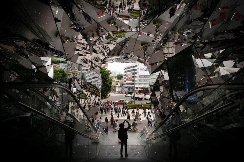 A tourist takes pictures in the entrance way to a shopping mall decorated with mirrors Saturday, May 18, 2019, in Harajuku district of Tokyo. (AP Photo/Jae C. Hong)