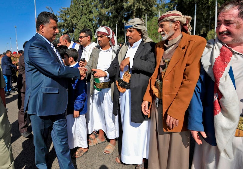 A member of the Huthi delegation (L) returning from peace talks in Sweden shake hands with supporters upon their arrival at Sanaa International Airport in the Yemeni capital on December 14, 2019.  / AFP / Mohammed HUWAIS
