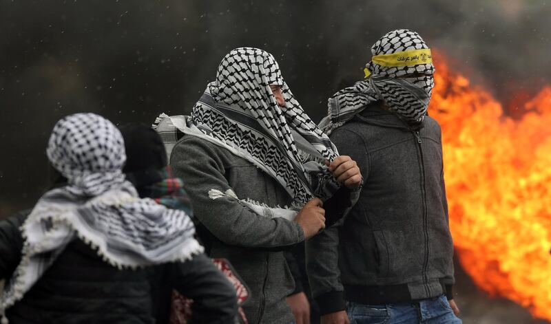 Palestinian protesters seek cover during clashes with Israeli forces. EPA