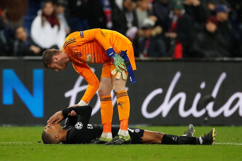 PSG forward Kylian Mbappe looks dejected as Manchester United's David de Gea stands over him after the match. Reuters