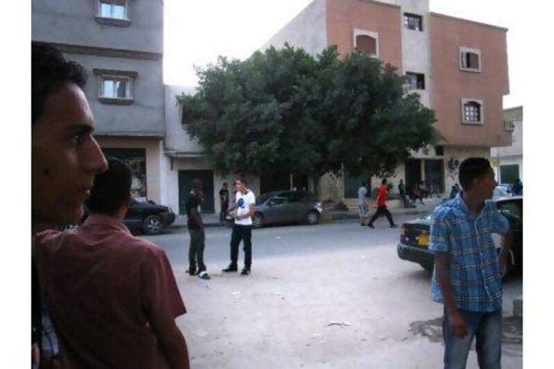 Locals in Misurati Street, in Tripoli's Abu Slim district. Youssef and Abdelkarim el Hazali were shot dead beneath the tree in the background last month by NTC fighters. (John Thorne / The National)