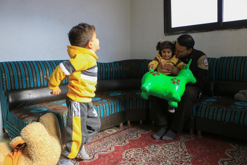 White Helmet volunteer Ahmed El-Masry at his home in Idlib city, playing with his children.