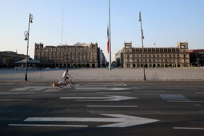 A cyclist walks his dog at an empty Plaza del Zócalo in Mexico City, Mexico. Getty Images