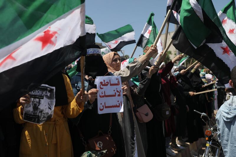 A Syrian woman holds a placard reading in Arabic 'boycott because you are a human being' during a protest against the presidential elections, in Idlib. EPA