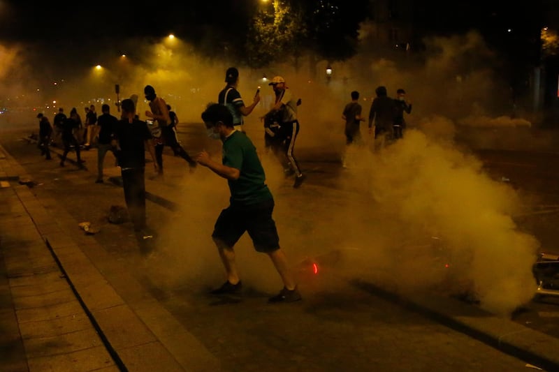 PSG supporters run through tear gas. AP