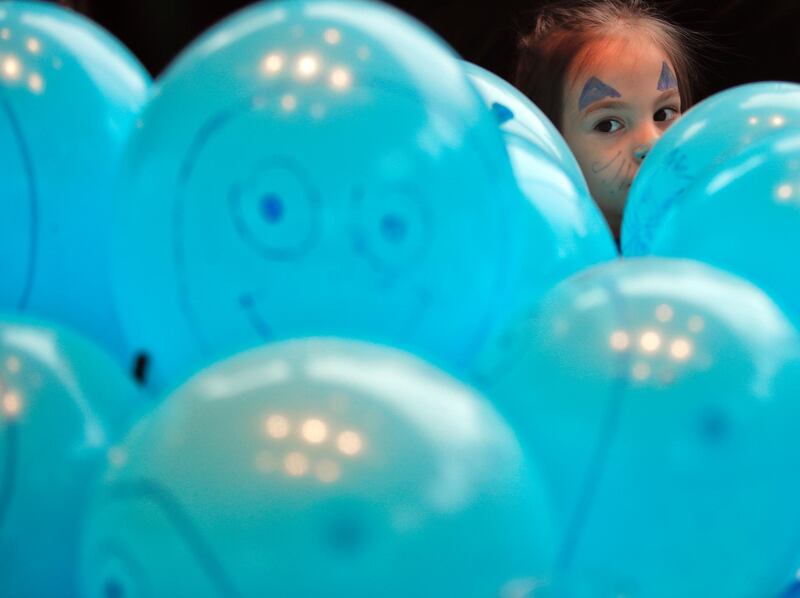 Six-year-old Antonia peers from behind blue balloons during a UNICEF Romania-organised event celebrating World Children's Day in Bucharest. AP