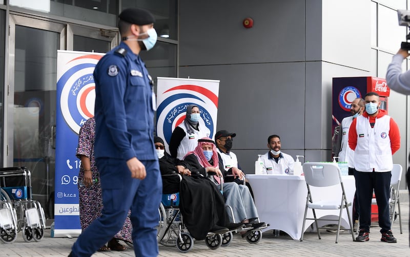 People wait outside a vaccination centre in Kuwait City. EPA