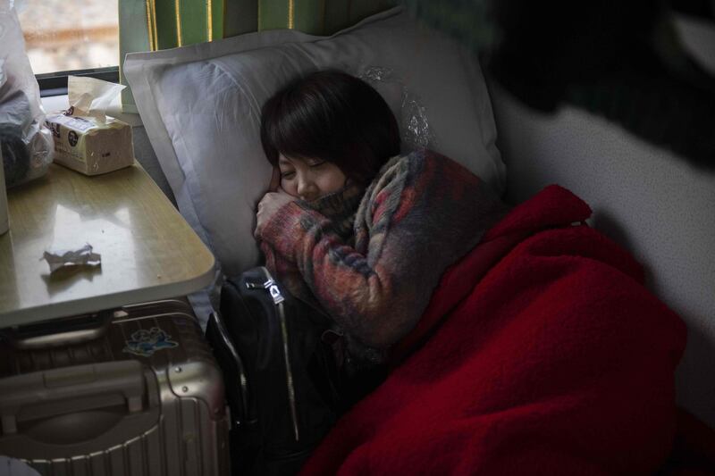 A passenger rests in a sleeping bunk on a train in Beijing as she heads back to her hometown. AFP