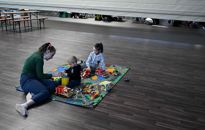 Ukrainian refugees play on the floor in the sports hall. AFP