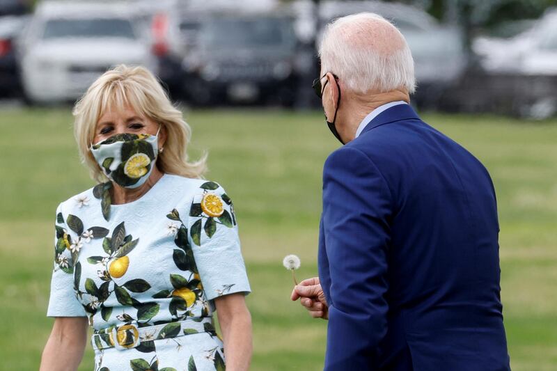 U.S. President Joe Biden stops to pick a dandelion for first lady Jill Biden as they walk to board the Marine One helicopter on the Ellipse near the White House in Washington, U.S., April 29, 2021.  REUTERS/Jonathan Ernst     TPX IMAGES OF THE DAY