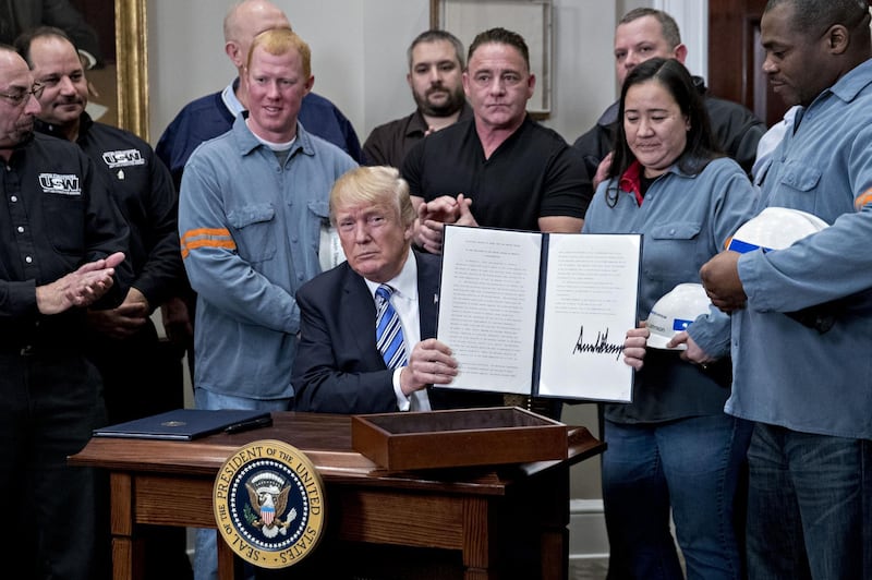 U.S. President Donald Trump holds up a signed proclamation on adjusting imports of steel into the United States next to steel and aluminum workers in the Roosevelt Room of the White House in Washington, D.C., U.S., on Thursday, March 8, 2018. Trump signed the order over steel and aluminum tariffs that he said could spare certain countries if they have strong trading and military ties with the U.S. telling reporters earlier that Mexico and Canada would likely not face the levies if they renegotiate the North American Free Trade Agreement. Photographer: Andrew Harrer/Bloomberg