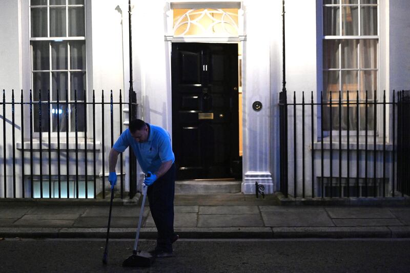 A worker cleans outside No 11 Downing Street before the budget. EPA
