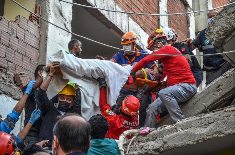 Rescuers and local volunteers carry a wounded victim on a stretcher from a collapsed building after a powerful earthquake struck Turkey's western coast and parts of Greece, in Izmir. AFP