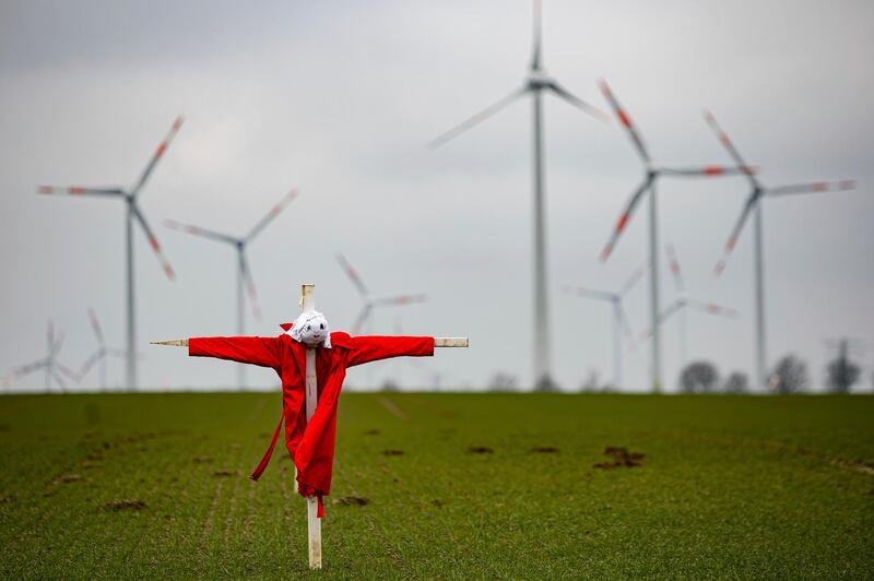 A scarecrow stands in a field in front of wind turbines near the city of Salzgitter in Lower Saxony, Germany. dpa via AP