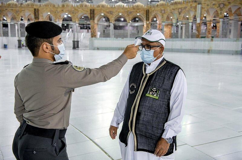 A security man checks the temperature of a worker as they work on raising the Kiswa, a silk cloth covering the Holy Kaaba, before the annual pilgrimage season, at the Grand Mosque in Mecca, Saudi Arabia. REUTERS