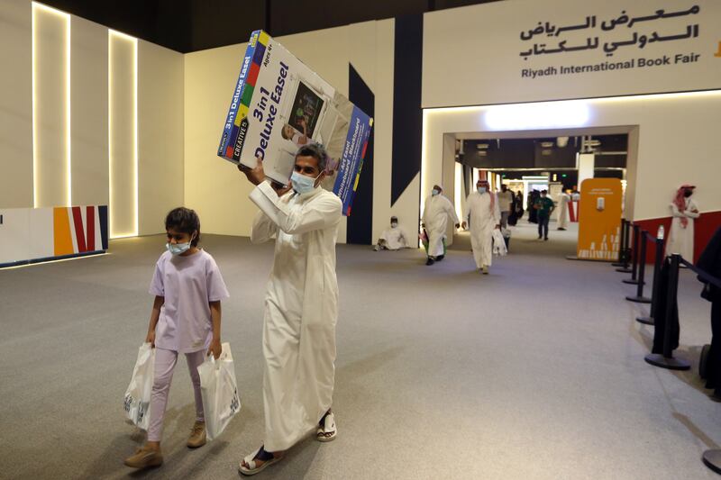 A Saudi man and his daughter carry books and educational toys.