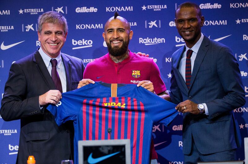 epa06930786 FC Barcelona's third vice president Jordi Mestre (L) and Sports Manager Eric Abidal (R) pose next to Chilean midfielder Arturo Vidal during his presentation as new player of the team, in Barcelona, northeastern Spain, 06 August 2018. Vidal has signed with the Spanish club for the next three seasons.  EPA/Enric Fontcuberta