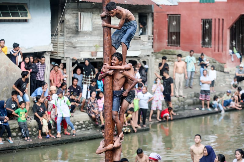 Men climb a pole coated in grease as they take part in a competition in Medan, North Sumatra, during celebrations to mark Indonesia's independence day. EPA