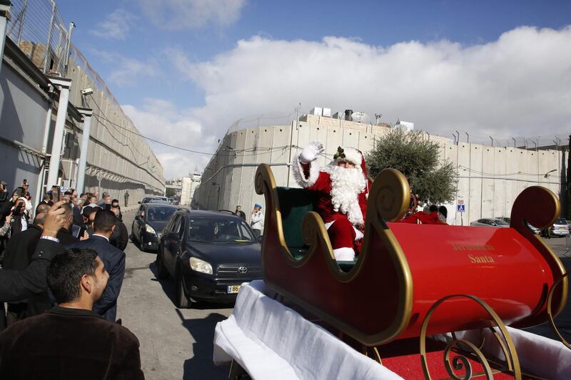 A Santa Claus on his slay precedes the convoy of Latin Patriarch of Jerusalem Pierbattista Pizzaballa, passing near the controversial Israeli separation barrier, as he arrives in the West Bank city of Bethlehem. AFP