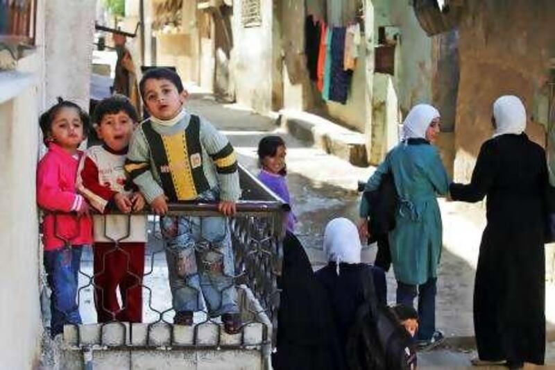 Palestinian children, left, are seen on a balcony, while a group of school girls are seen walking in an alley of Baqaa Palestinian refugee camp northwest of Amman, Jordan, Sunday, Dec. 6, 2009. (AP Photo/Nader Daoud)