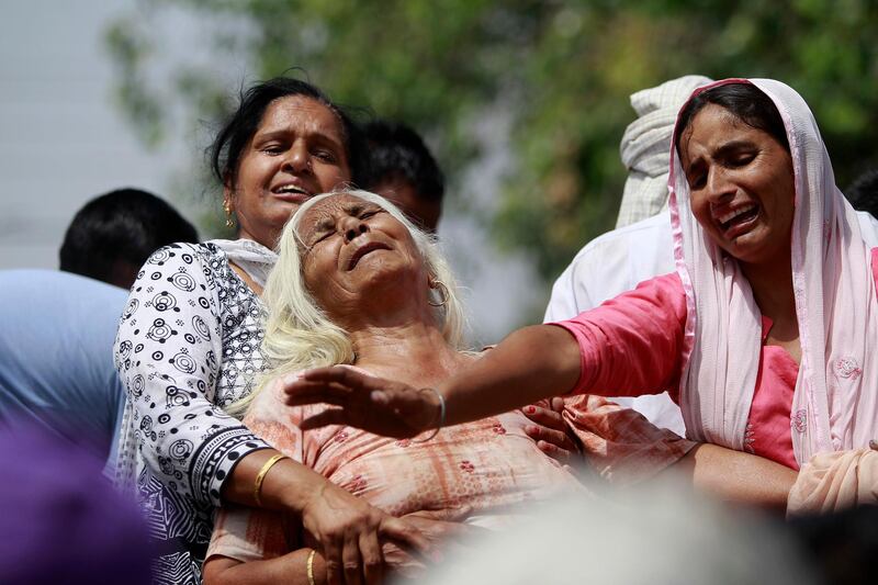 Indian women wail near the bodies of relatives, victims of cross-border firing, as they block a road during a protest against the state government in Ranbir Singh Pura, Jammu and Kashmir state, India, Friday, May 18, 2018. Eight civilians, including a husband and wife and four members of a family, were killed after Indian and Pakistani soldiers targeted border posts and villages along the highly militarized frontier in disputed Kashmir, officials said Friday. An Indian soldier was also killed in the fighting. (AP Photo/Channi Anand)