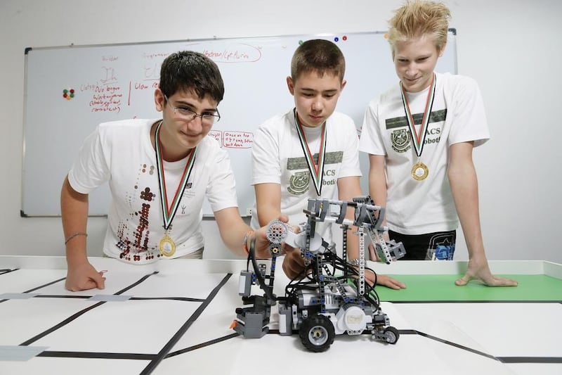 Pupils Sebastian Thaeron, 14, Christian Warren, 14, and Marnix Roelfs, 14, show off their winning robot, Arken Olympus, at the American Community School in Abu Dhabi. Sarah Dea / The National
