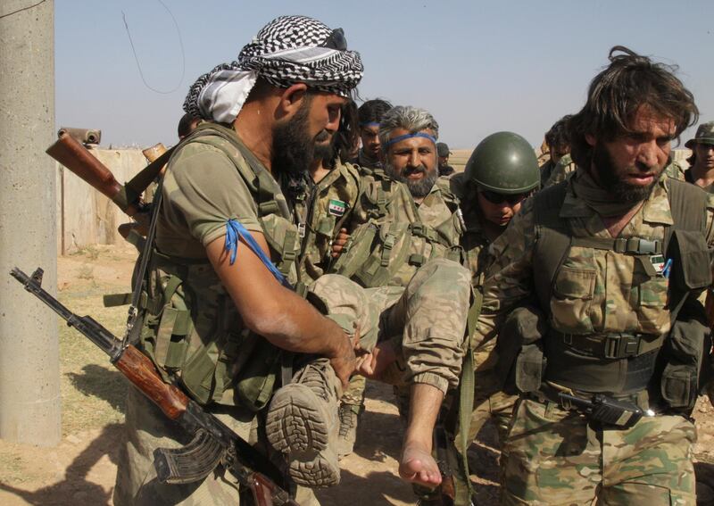 Turkish-backed Syrian opposition fighters evacuate an injured fellow combatant in Tel Abyad, Syria.  AP