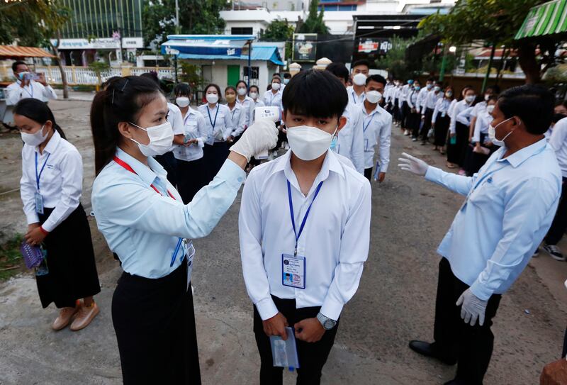 Workers check the body temperatures of pupils arriving for Year 12 examinations at a school in Phnom Penh, Cambodia. EPA