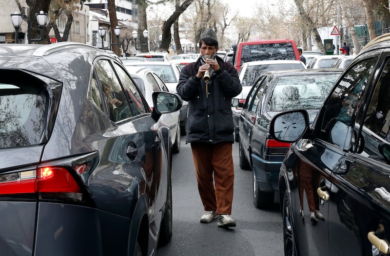 An Iranian man plays music among the cars to collect money during Norwuz. EPA