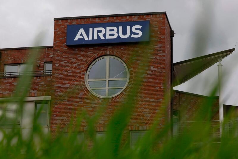 The Airbus logo can be seen on a building next to the main entrance of the Hamburg plant of European aircraft maker Airbus is seen on July 8, 2020. Airbus said it is planning to cut around 15,000 jobs worldwide, 11 percent of its total workforce, in response to the "gravest crisis" the industry has ever seen. / AFP / MORRIS MAC MATZEN
