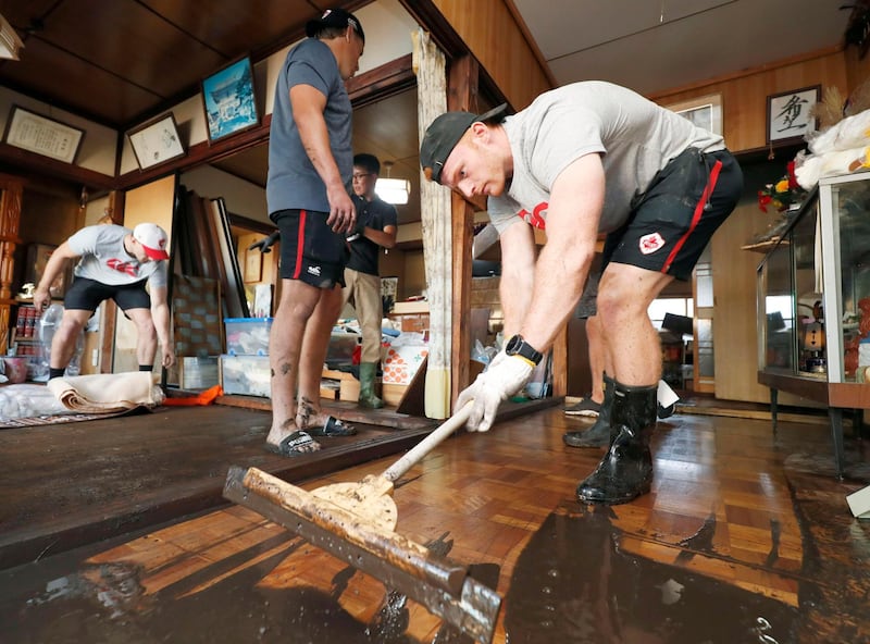 Canadian player Peter Nelson, right, volunteers to clean up mud in a house in Kamaishi, Iwate prefecture,  Japan, following the cancellation of their Rugby World Cup Pool B match against Namibia due to Typhoon Hagibis. AP