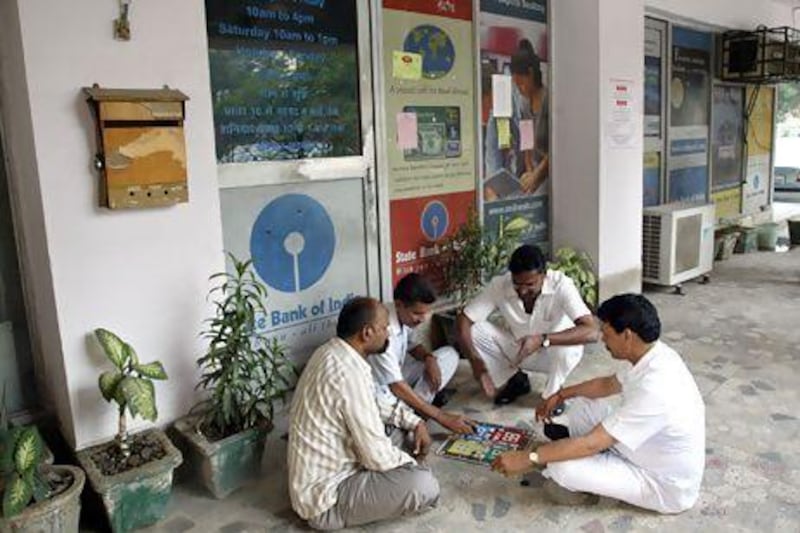 Drivers play a board game in front of a closed door outside the State Bank of India in New Delhi.
