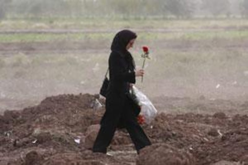 A relative carries roses for victims as she visits the scene of the crash of an Iranian passenger plane near Qazvin, north-west of Tehran, that claimed 168 lives.