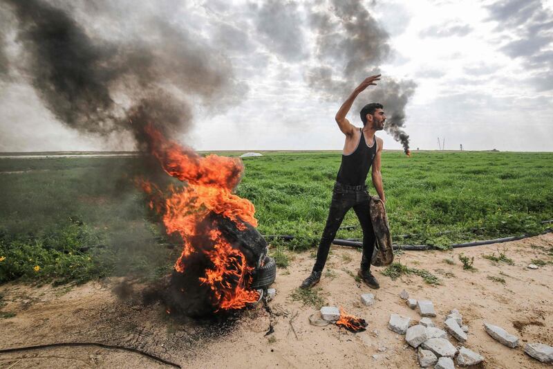 A Palestinian man sets fire to tyres along the Gaza-Israel border east of Khan Yunis in the southern Gaza Strip after Israeli army extracted a body with a bulldozer.